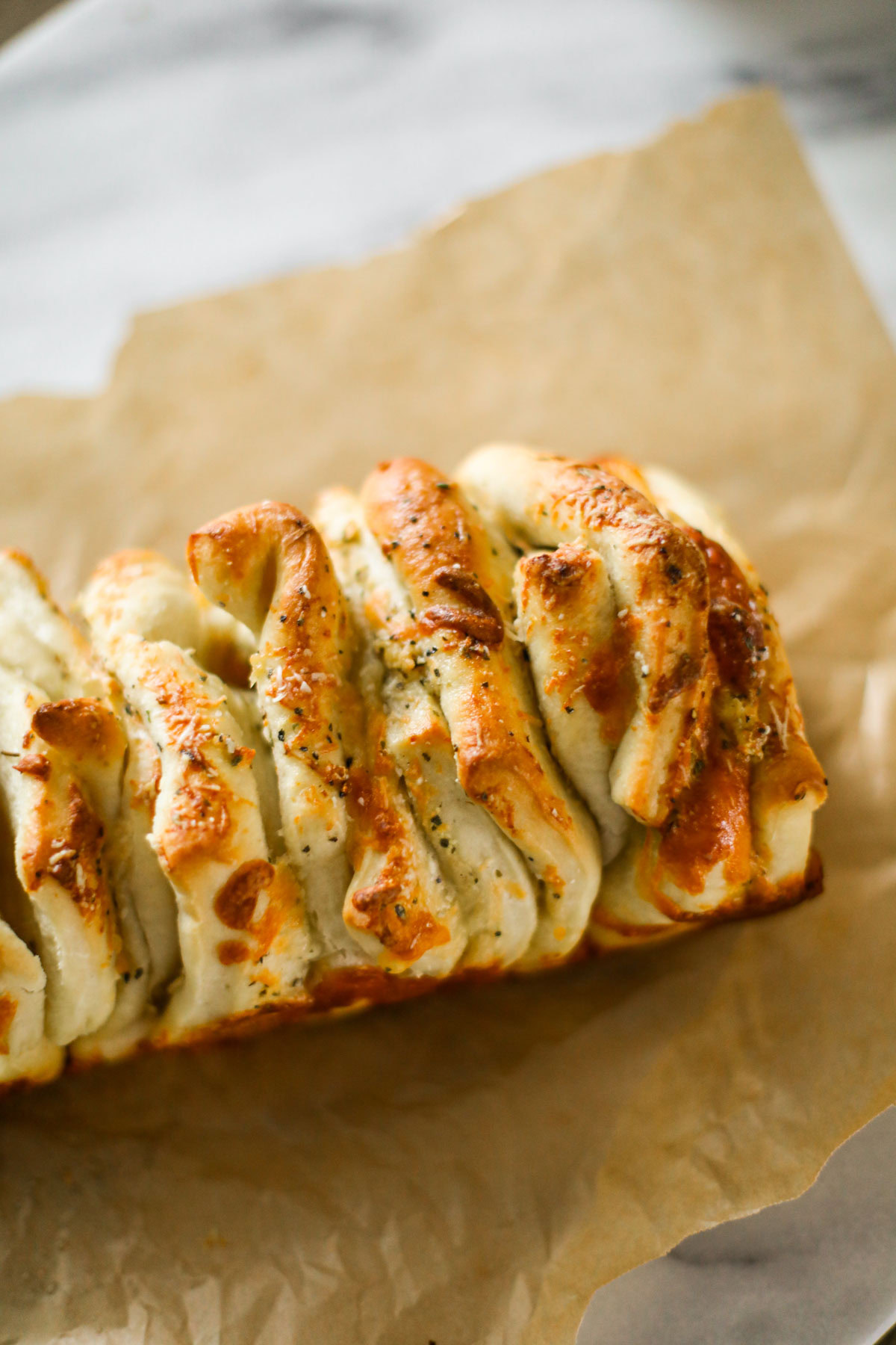 Garlic pull apart loaf on parchment paper with golden, cheesy layers