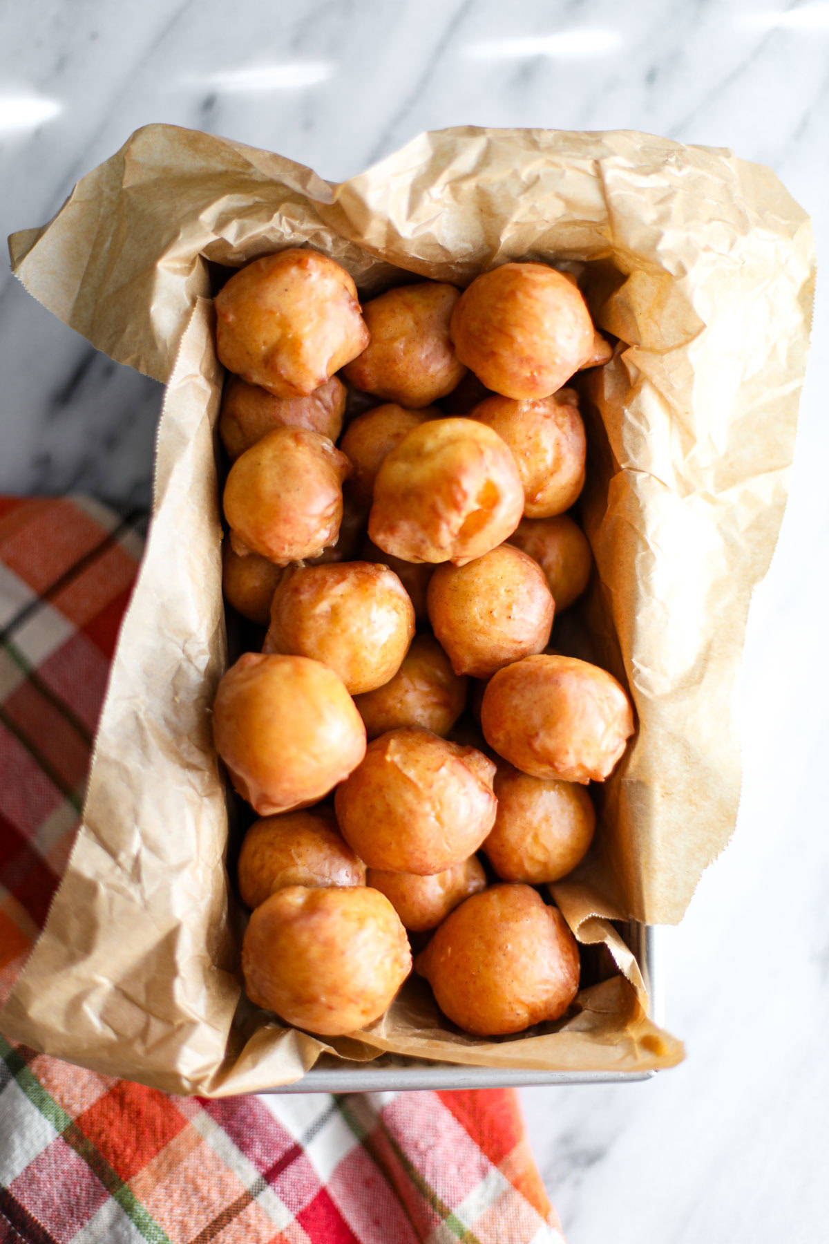 Glazed pumpkin donut holes in a metal tin.