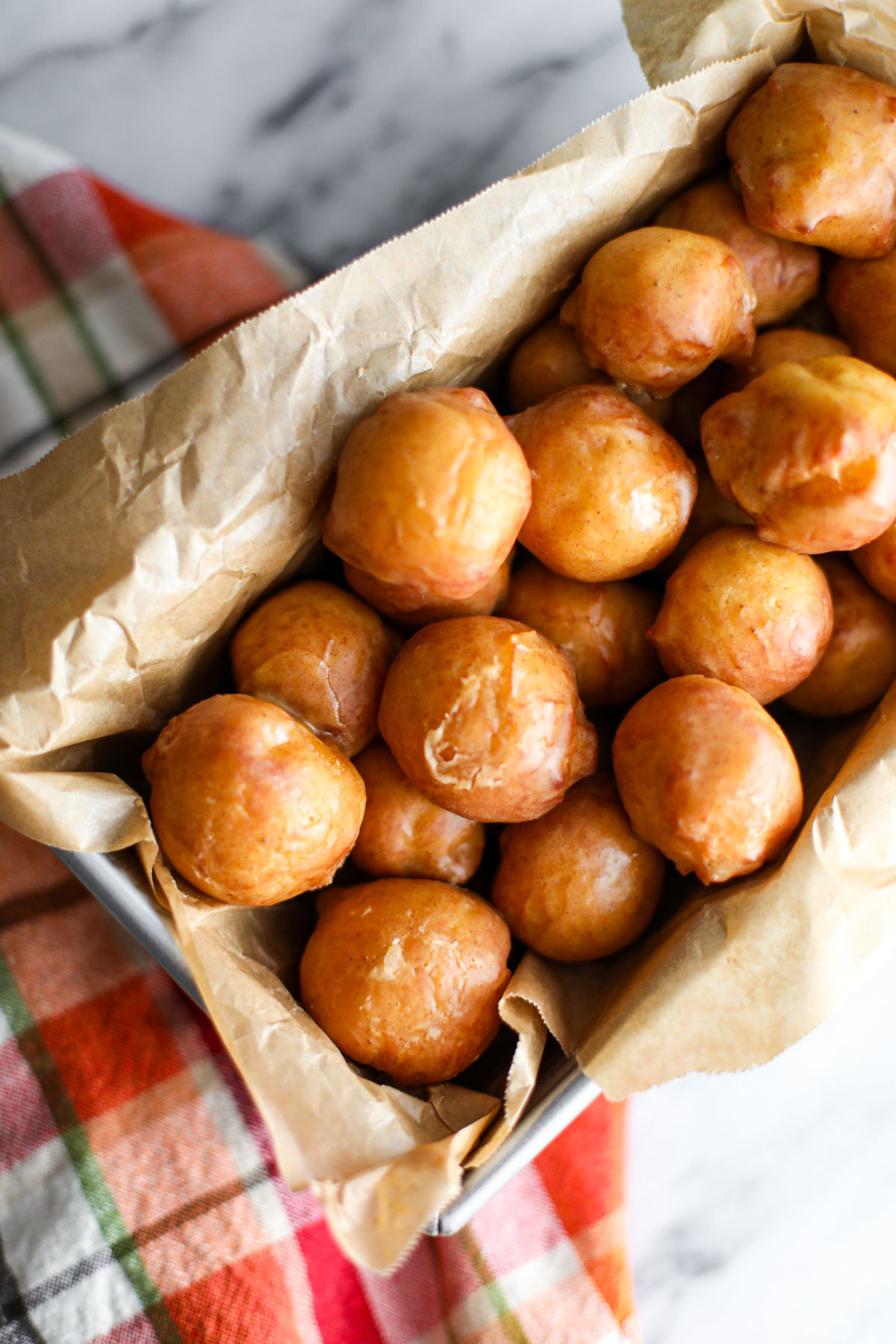 Glazed pumpkin donut holes in a metal tin.