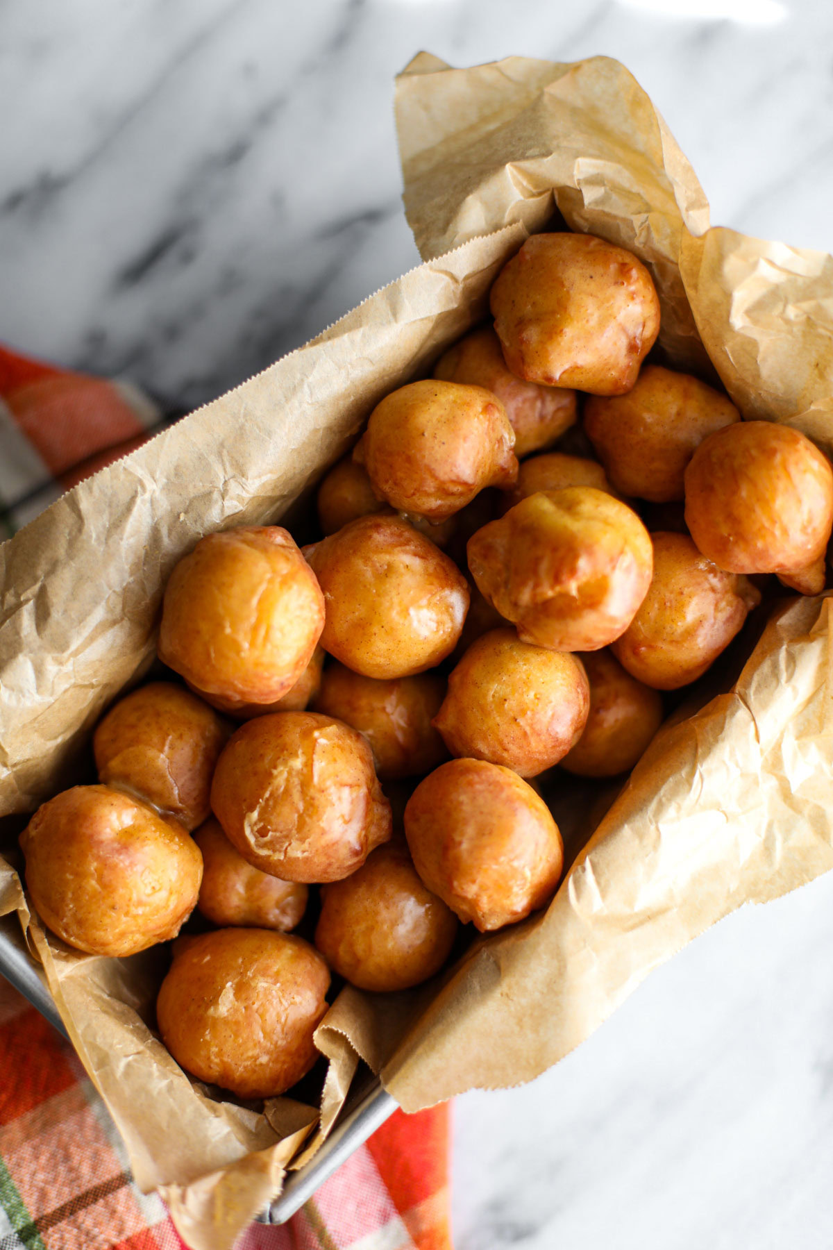 Glazed pumpkin donut holes in a metal tin.