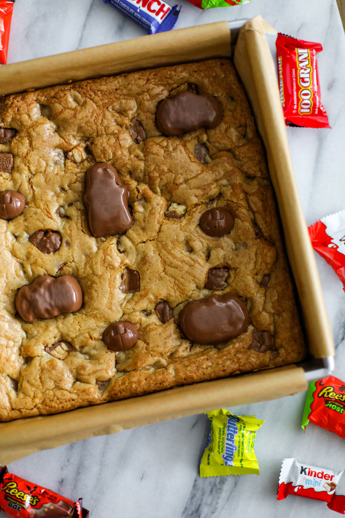 Baking pan of leftover Halloween candy cookie bars topped with chopped chocolate candy.
